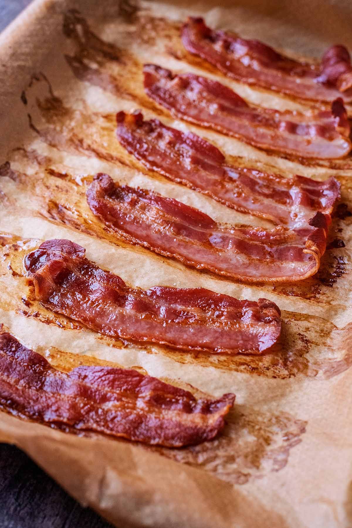 Cooked rashers of bacon on a lined baking sheet.