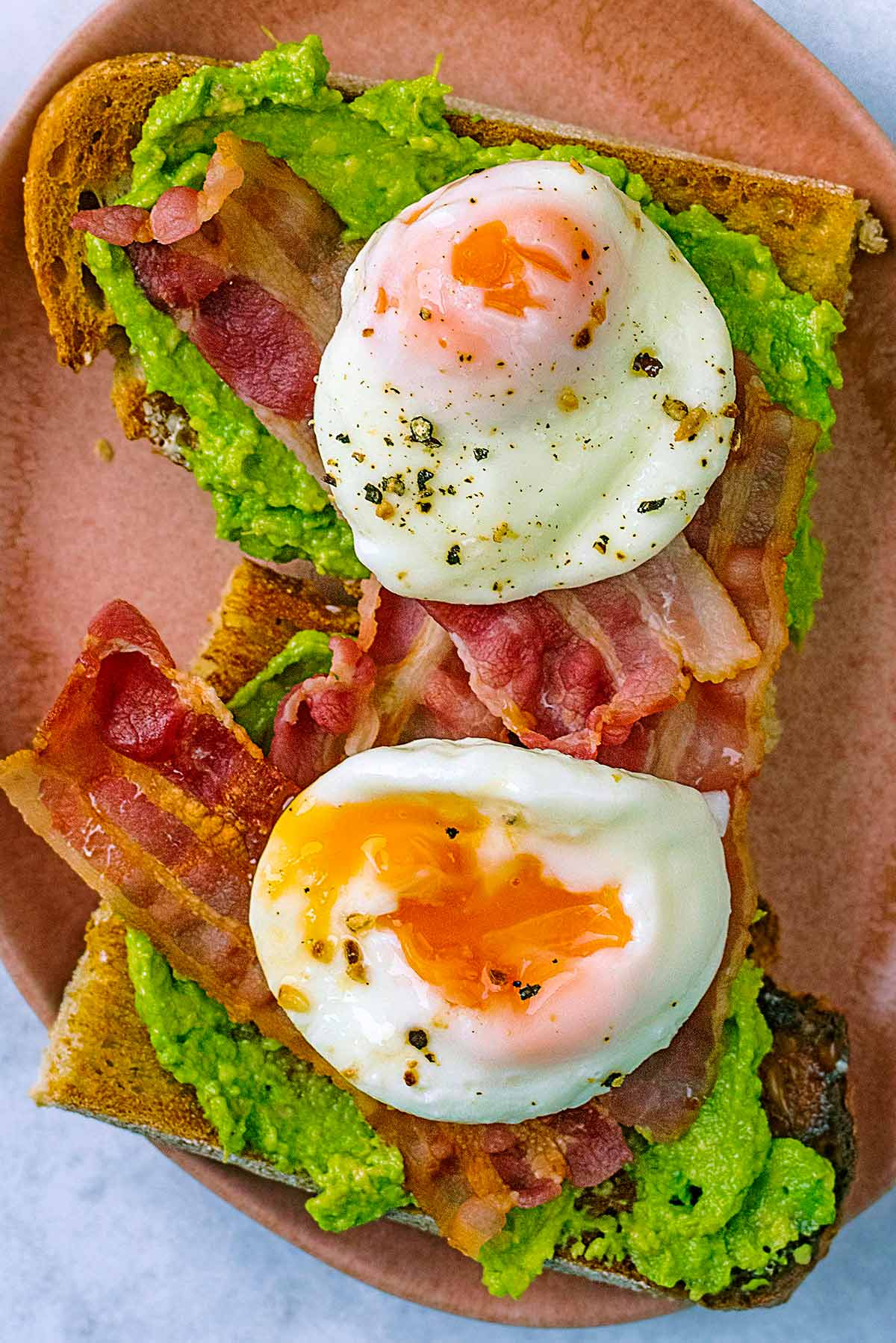 Avocado toast with bacon and poached eggs on it.