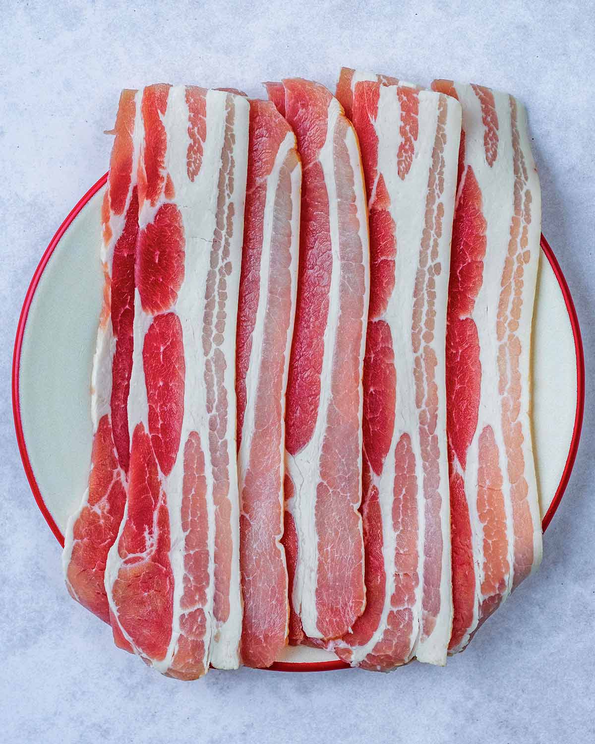 A plate of uncooked streaky bacon.