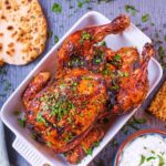 Roasted Harissa Chicken in a serving dish with a flatbread next to it.