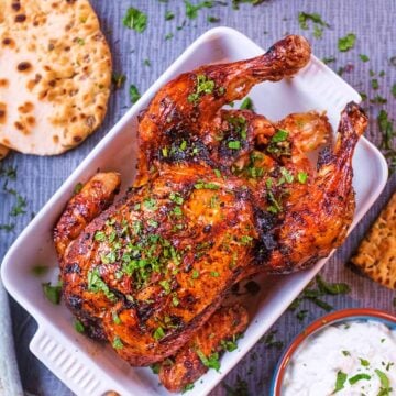 Roasted Harissa Chicken in a serving dish with a flatbread next to it.