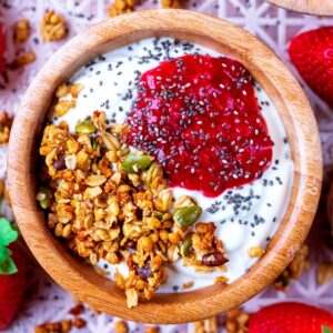 Strawberry puree topping a bowl of yogurt and granola.