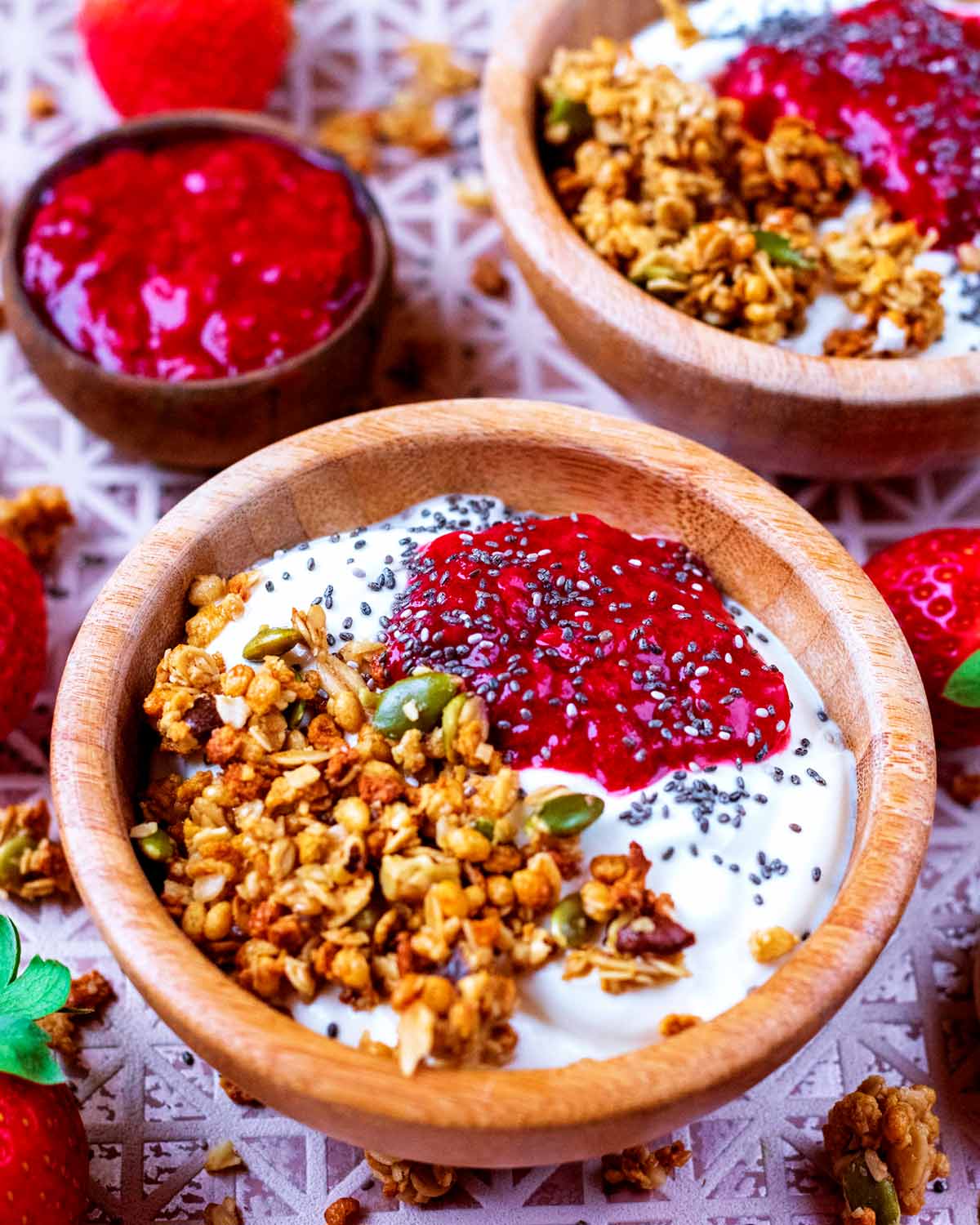 Yogurt, granola and strawberry jelly in a small wooden bowl, topped with chia seeds.