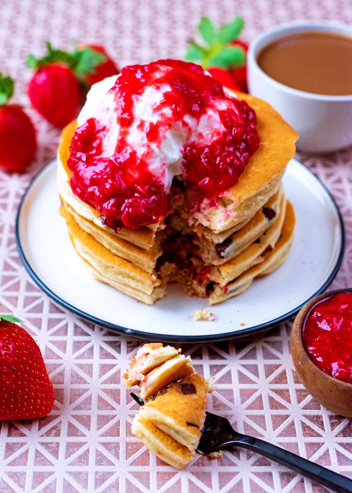 A stack of pancakes topped with cream and strawberry puree.