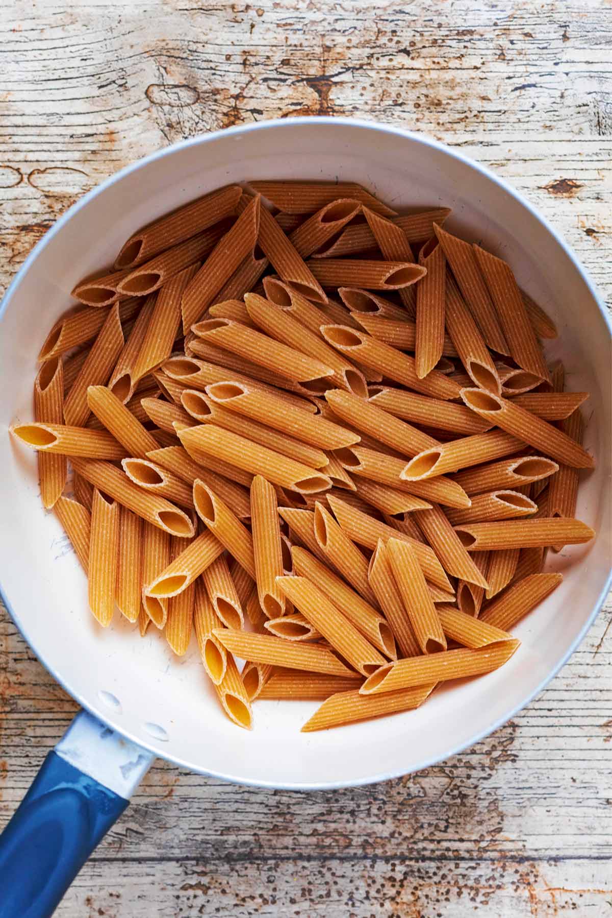 A saucepan full of uncooked penne pasta.