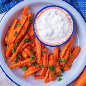 A plate of carrot fries with a small dish of dip.