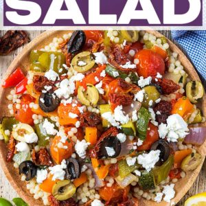 Roasted vegetable couscous salad on a wooden plate with a text title overlay.
