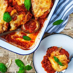 A plate of Healthy Eggplant Parmesan next to a baking tray with more of it in