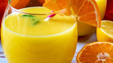 Two glasses of Immune Booster Juice next to orange and lemon halves.