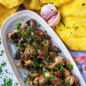 Roasted mushrooms in a long serving dish topped with chopped herbs