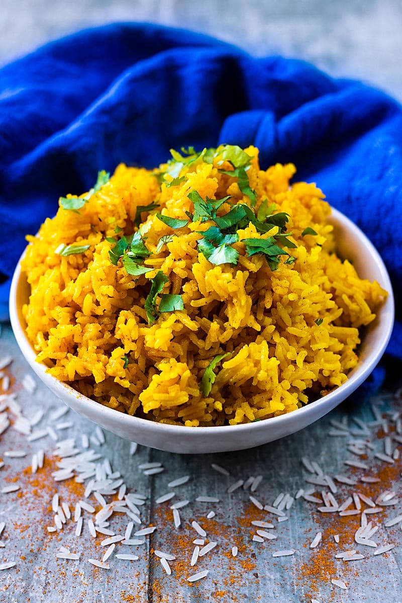 A bowl of yellow rice in front of a blue towel.