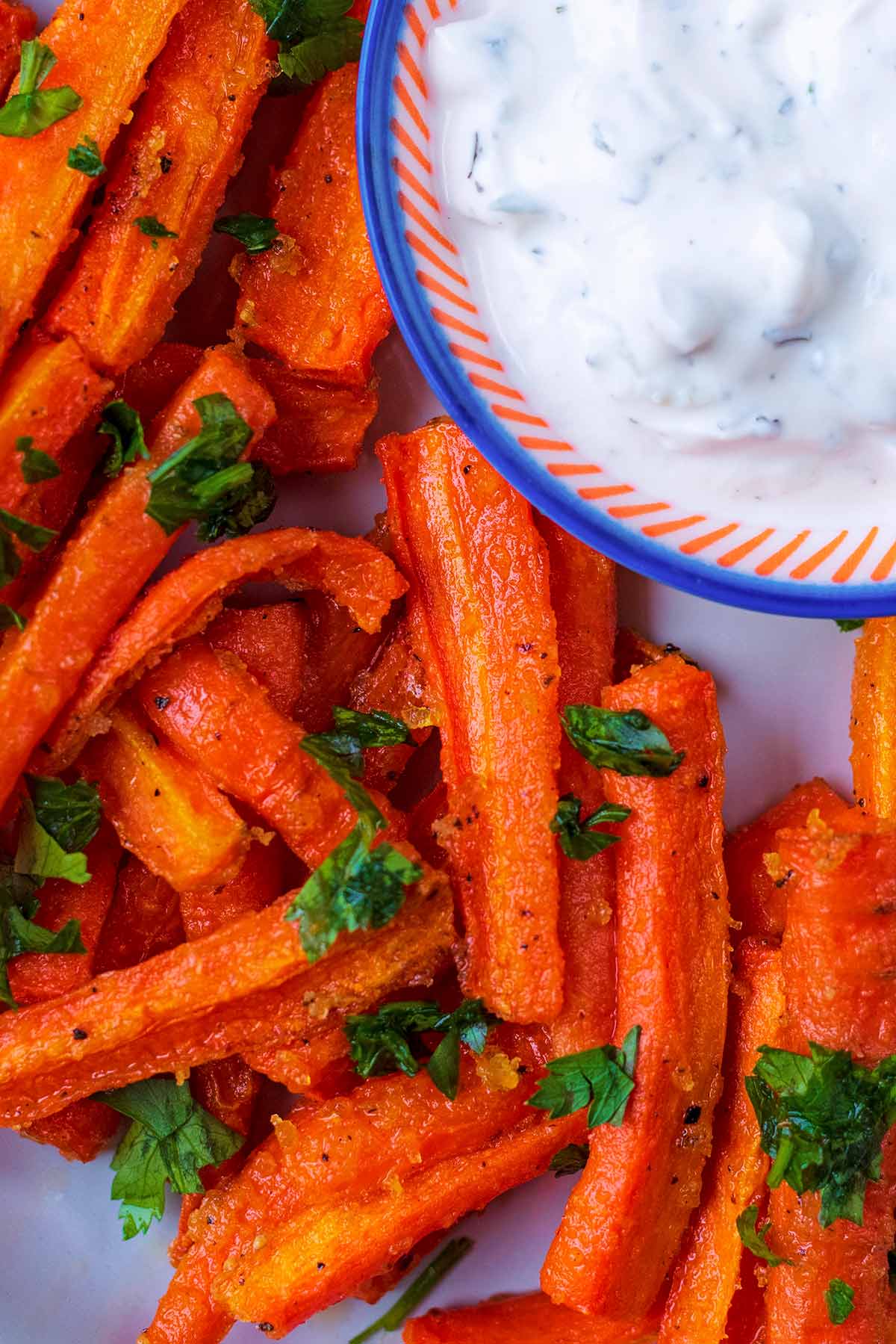 Carrot fries on a plate topped with chopped herbs.