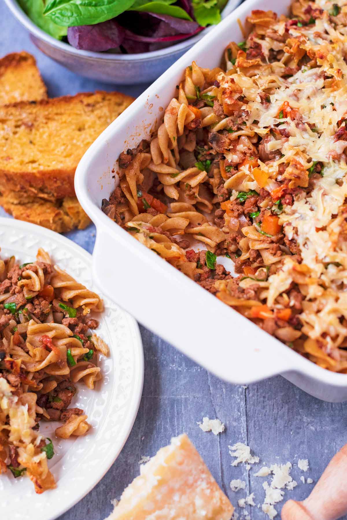 A baking dish of pasta bake with a portion removed.