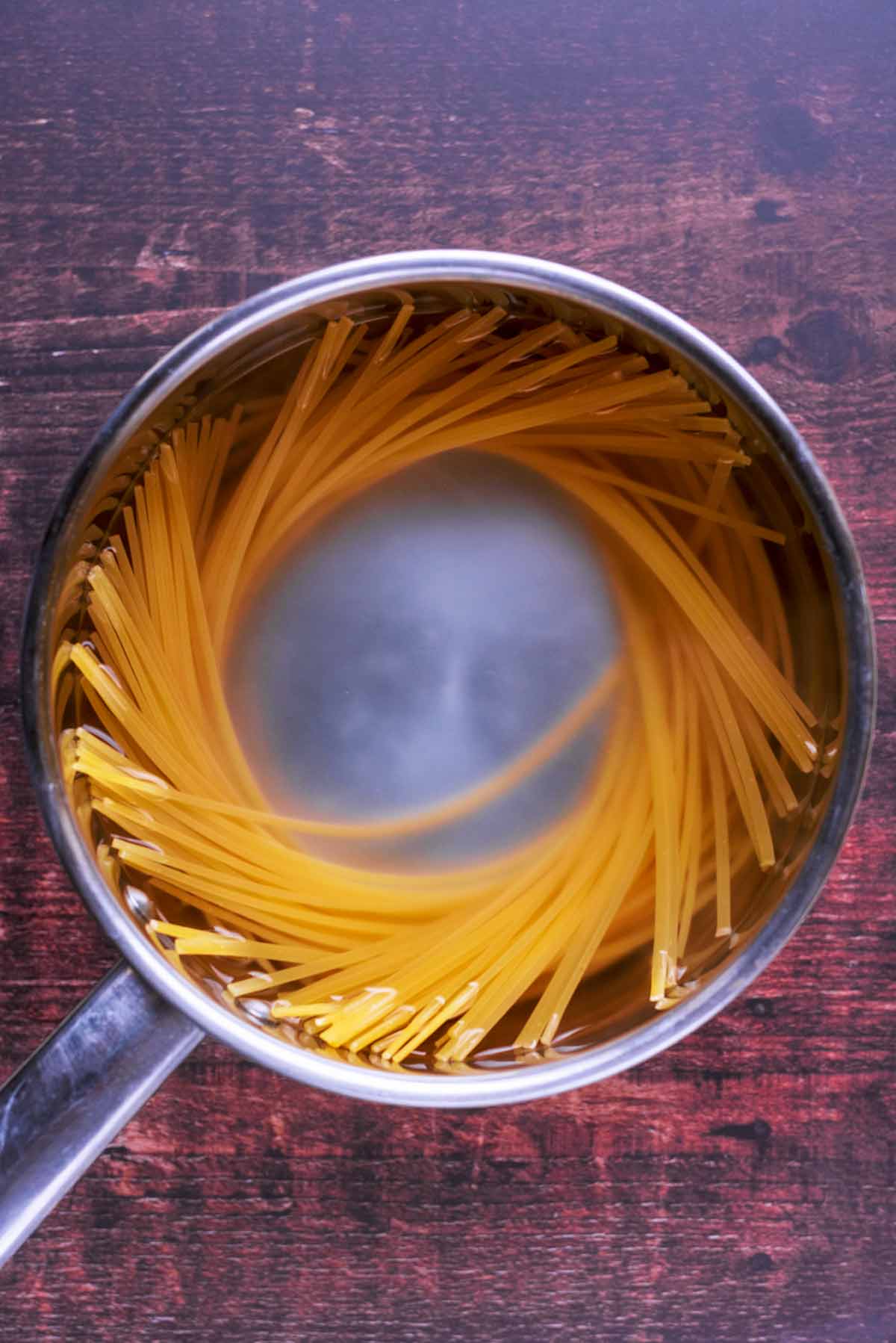 A saucepan with linguine cooking in it.