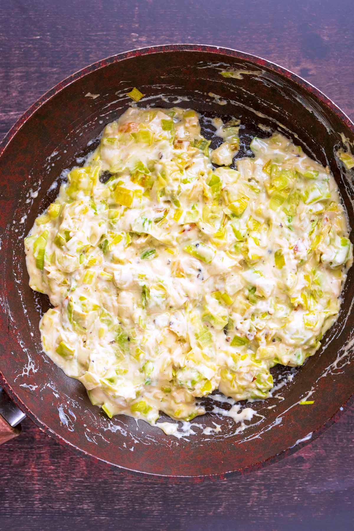 A creamy leek sauce cooking in a frying pan.