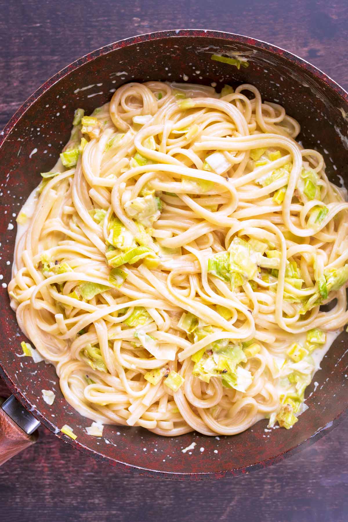 Creamy leek pasta cooking in a frying pan.