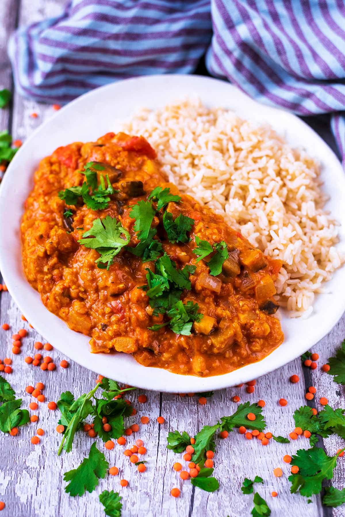 Curry and rice in a bowl with red lentils scattered around.