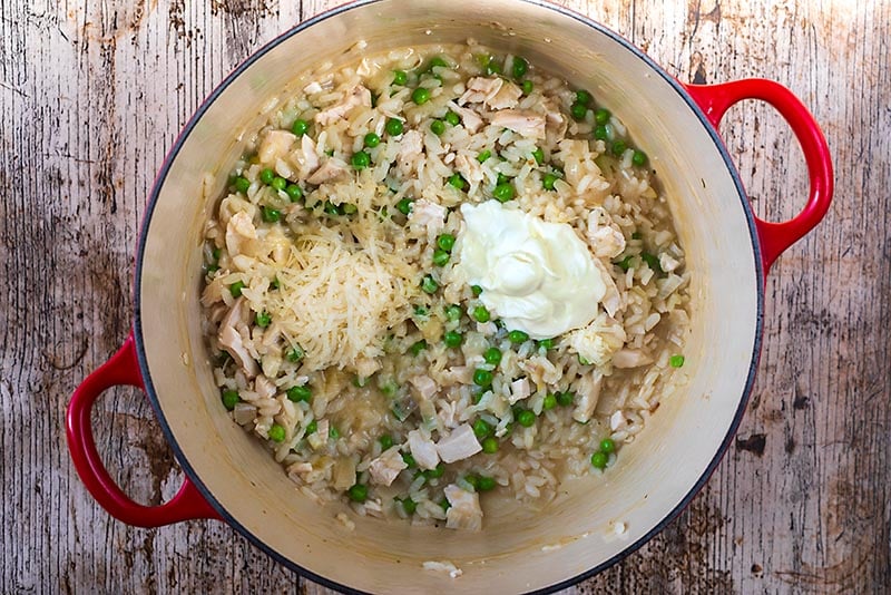 Chicken and Pea Risotto in a large cooking pot with cream and grated cheese.