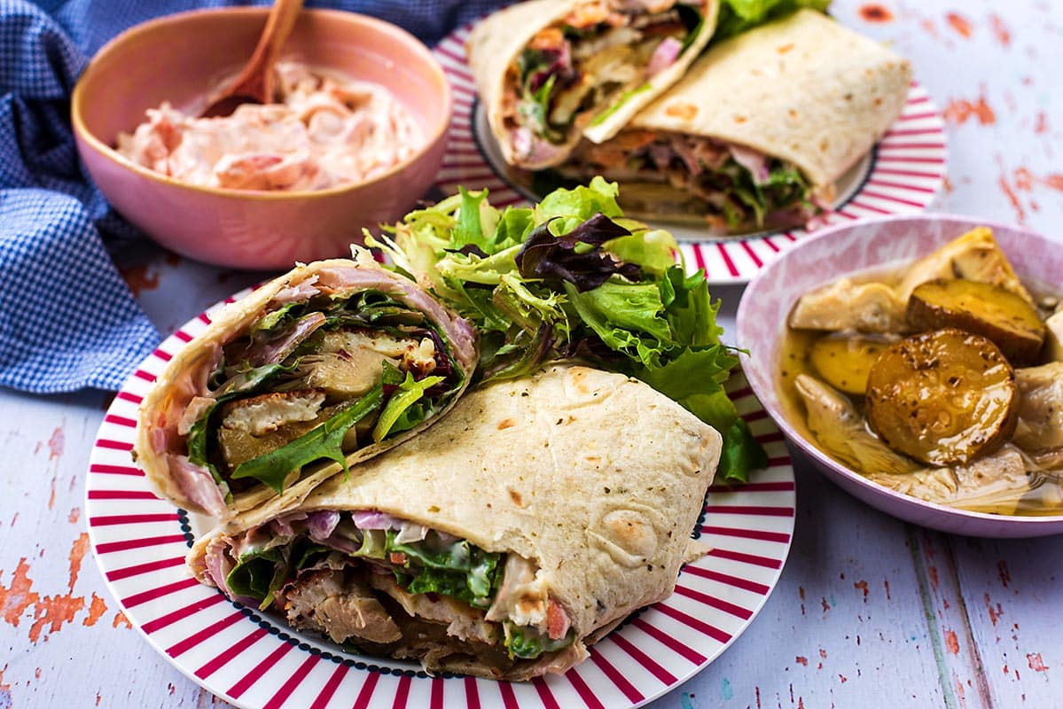 Greek Halloumi Wrap on a platenext to bowls of coleslaw and sliced zucchini