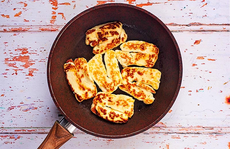 Slices of halloumi cooking in a frying pan