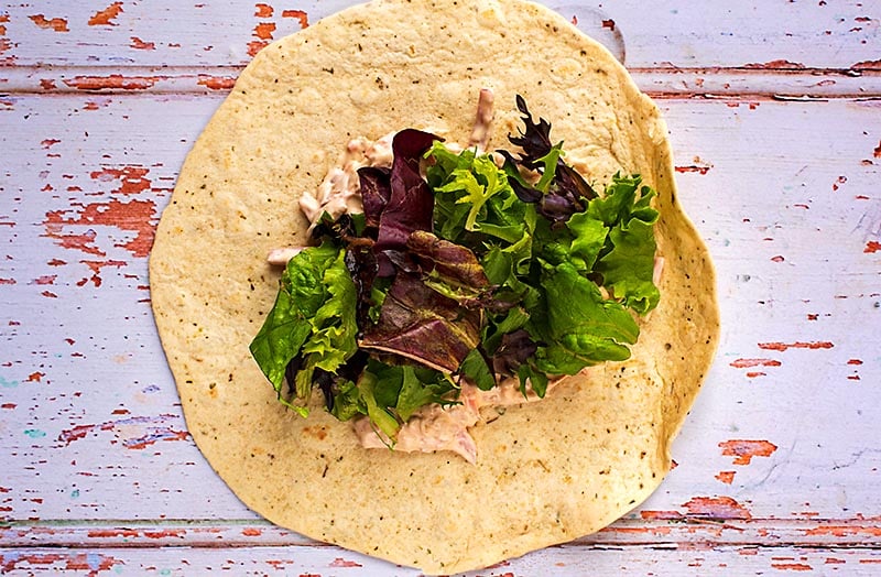 A tortilla wrap with coleslaw and salad leaves on it