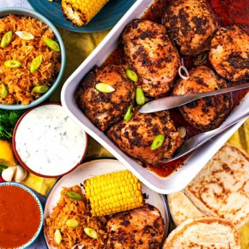 Peri Peri Chicken in a baking dish surrounded by corn, rice and dips.