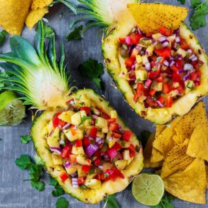 A halved and hollowed out pineapple fulled with salsa.