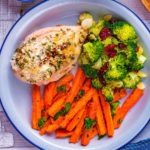 A stuffed chicken breast on a plate with carrots and broccoli.