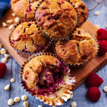 A pile of raspberry muffins on a wooden serving board