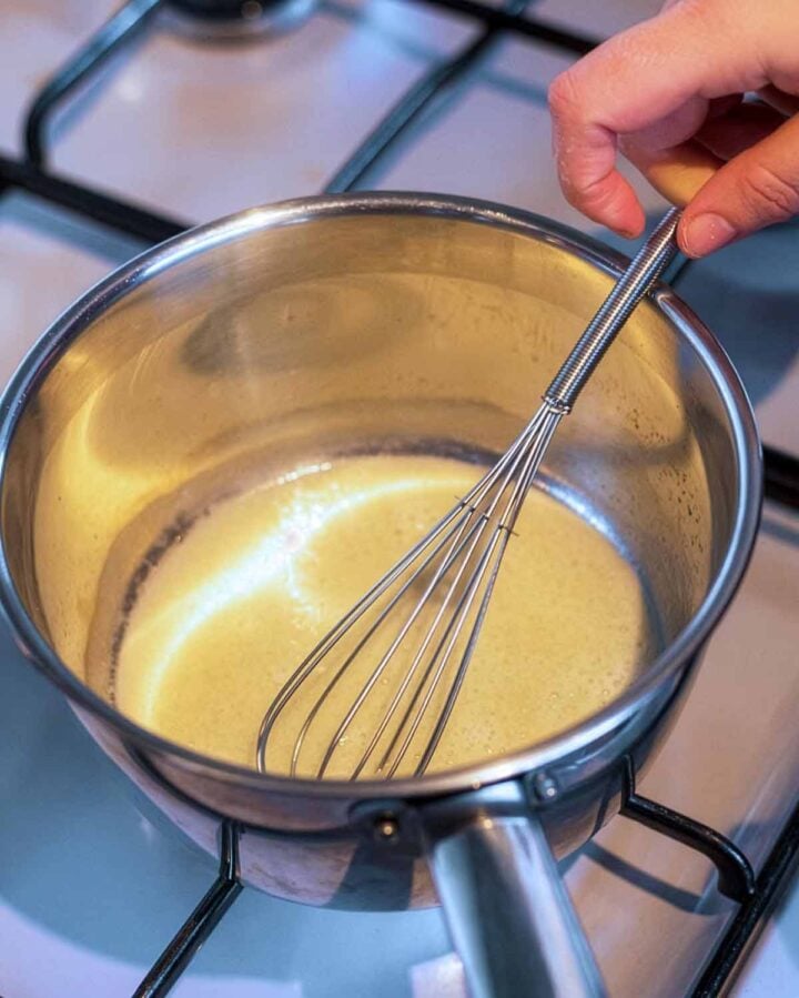 Oil and flour being whisked in a saucepan.