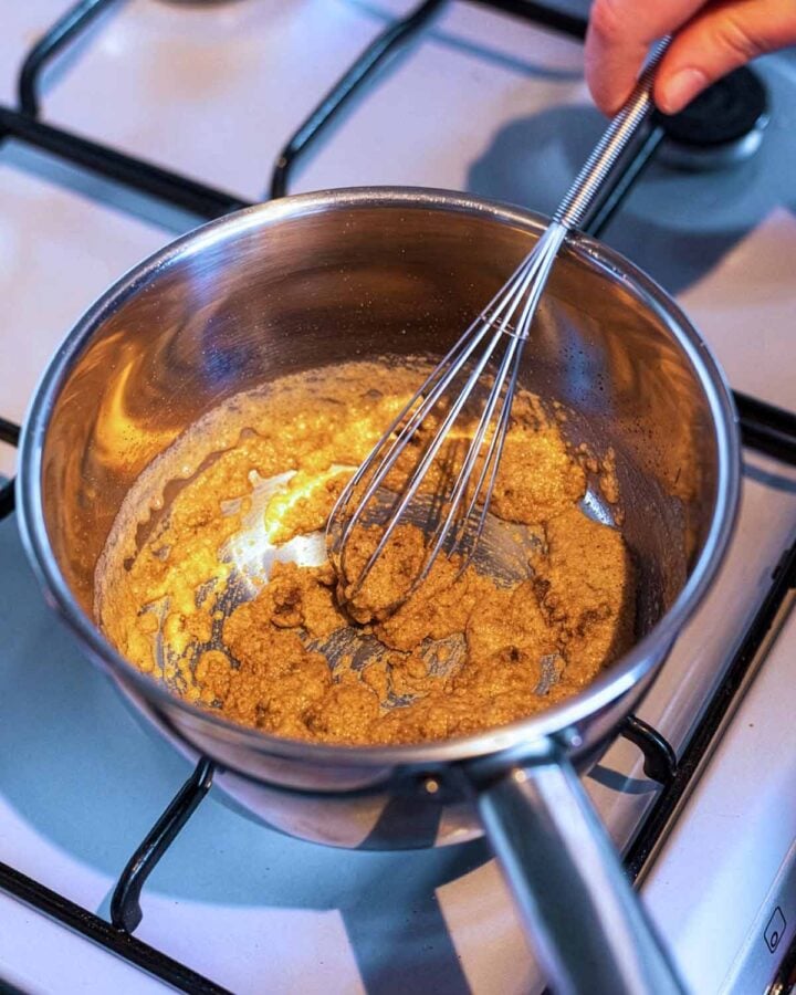 A brown paste being whisked in a saucepan.