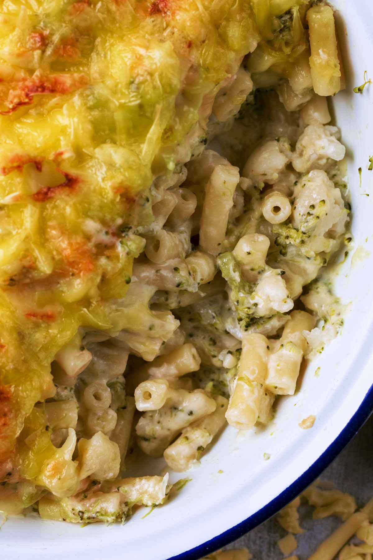 Cooked macaroni in a cheese sauce with finely chopped broccoli in it.