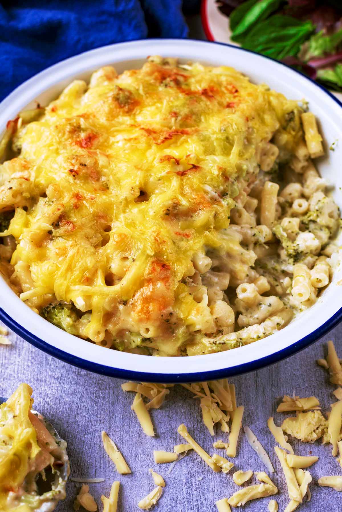 Macaroni Cheese in a dish surrounded by grated cheese.