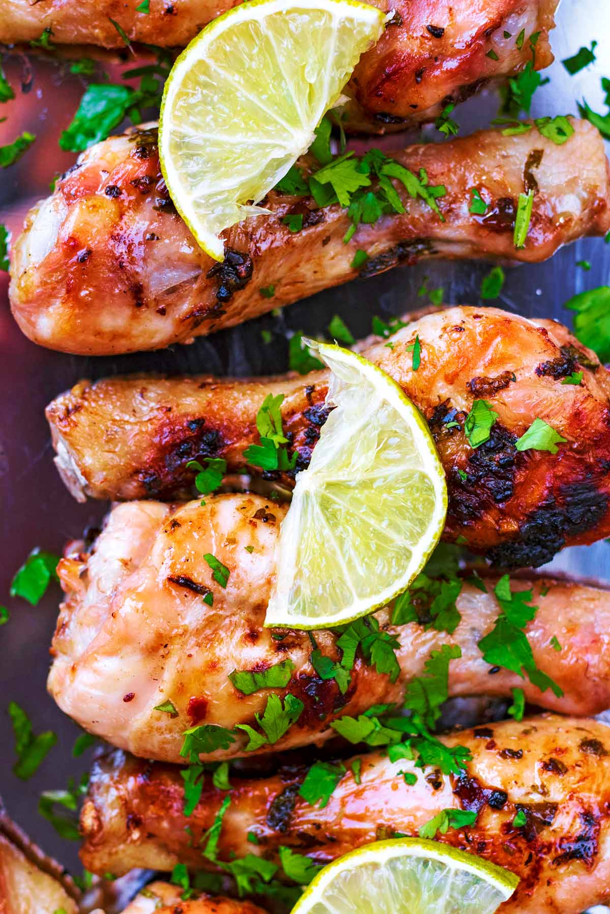 Cooked chicken drumsticks with lime slices on them.