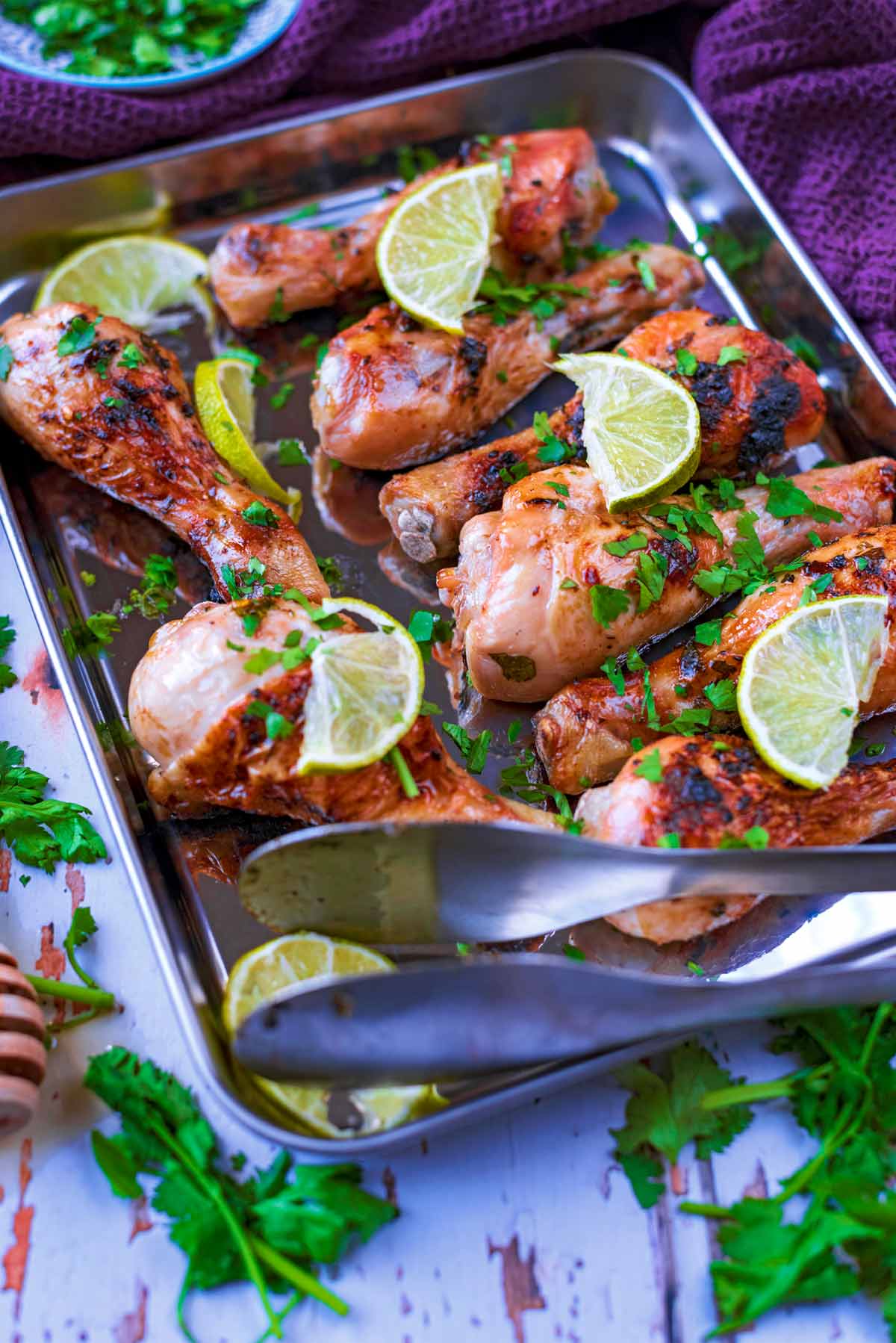 A baking tray with chicken and limes on it