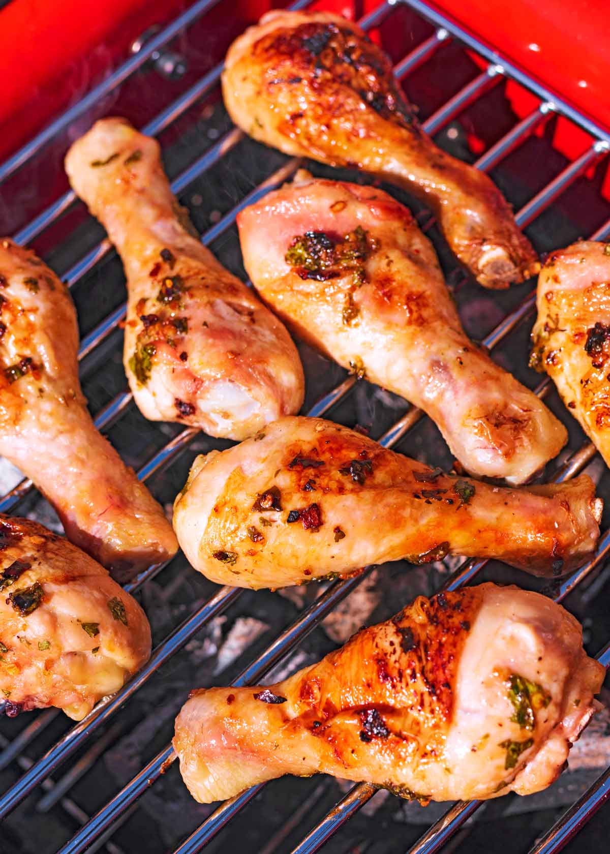 Chicken drumsticks cooking on a barbecue grill.