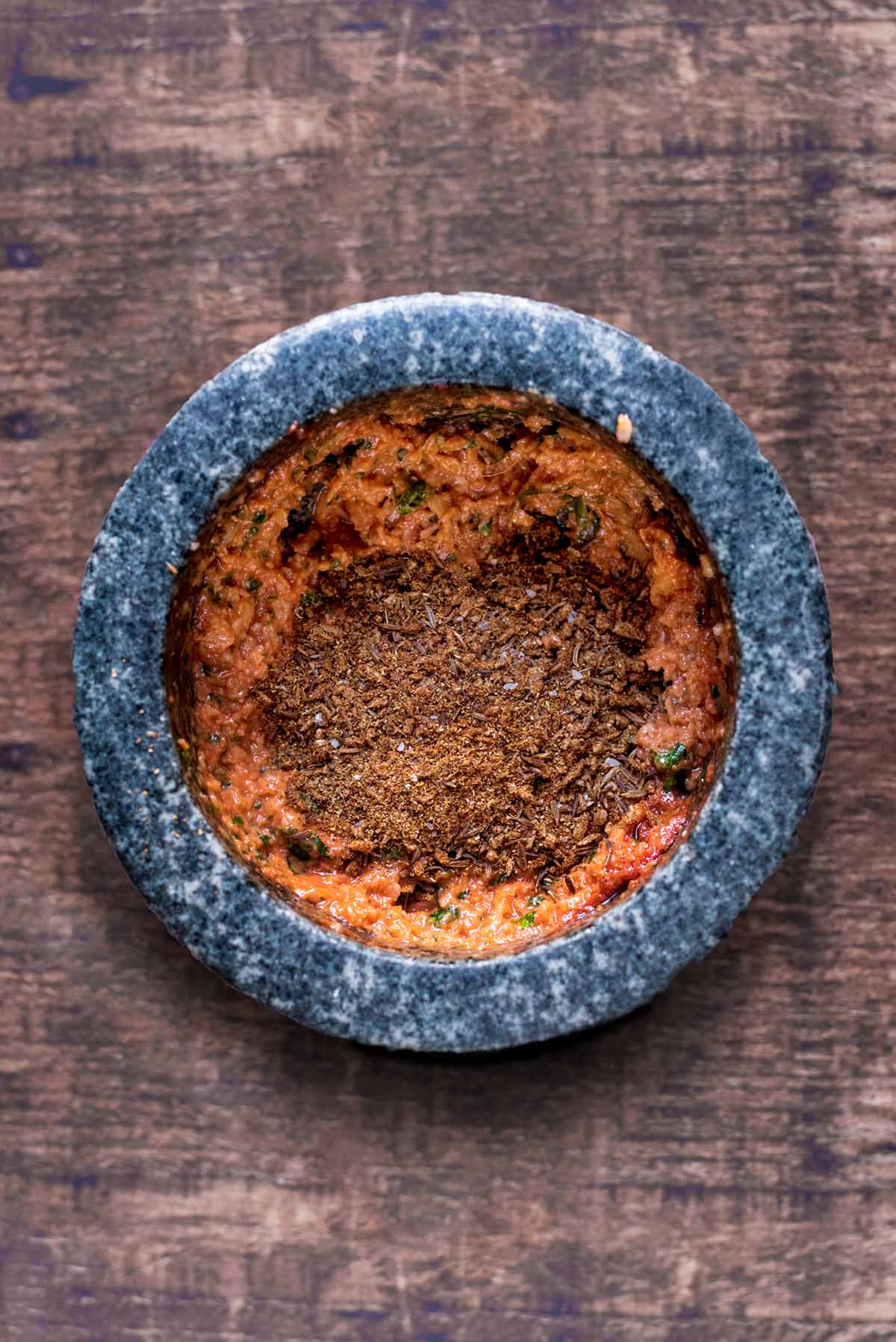 A pestle and mortar containing curry paste and spices.