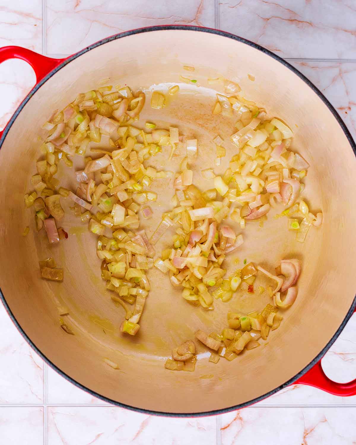 A large pan with chopped onions cooking in it.