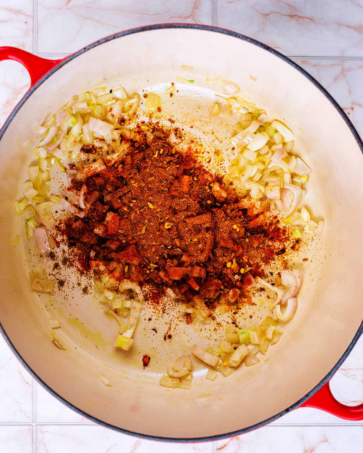 A large pan with chopped onions and spices cooking in it.