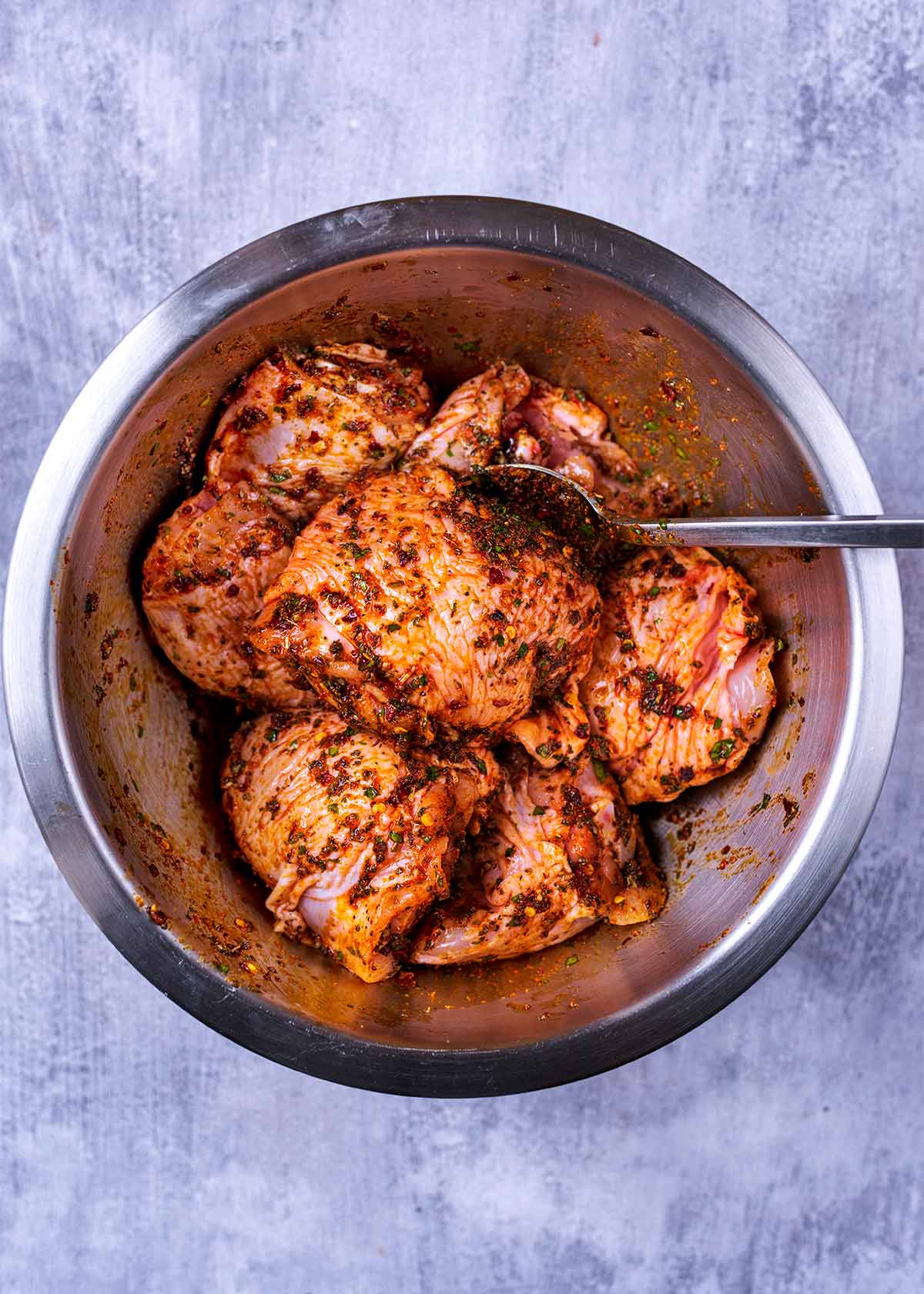 A bowl of chicken thighs coated in a marinade.