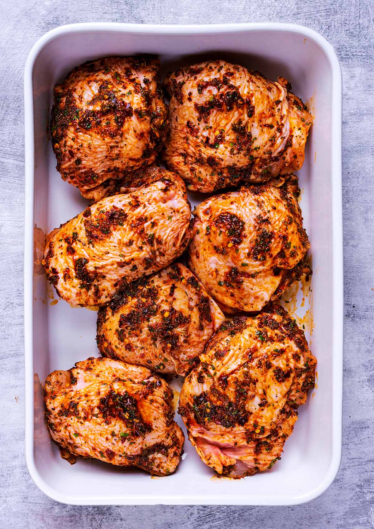 Marinated chicken thighs in a baking dish.