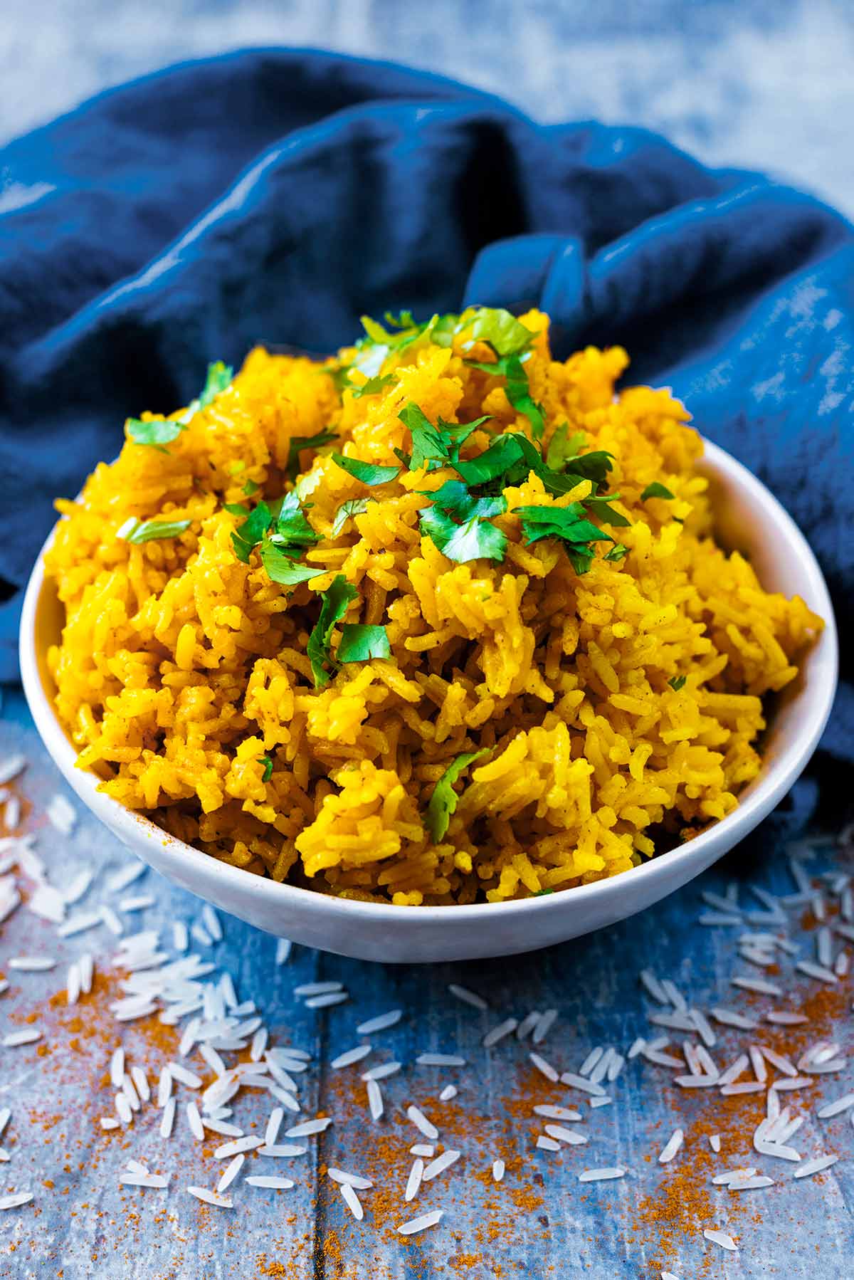 A bowl of yellow rice in front of a blue towel.