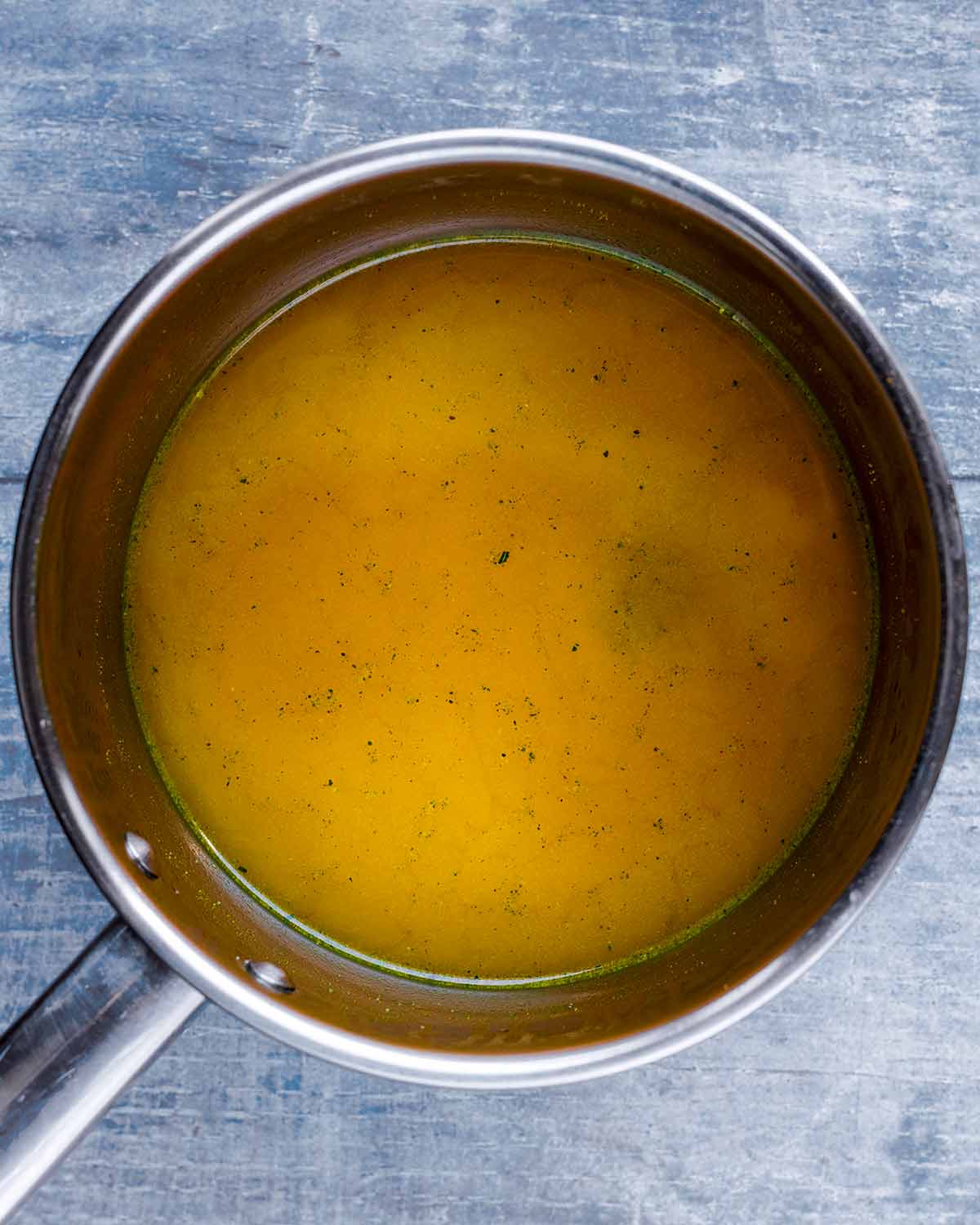 A stainless steel saucepan containing a yellow coloured liquid.