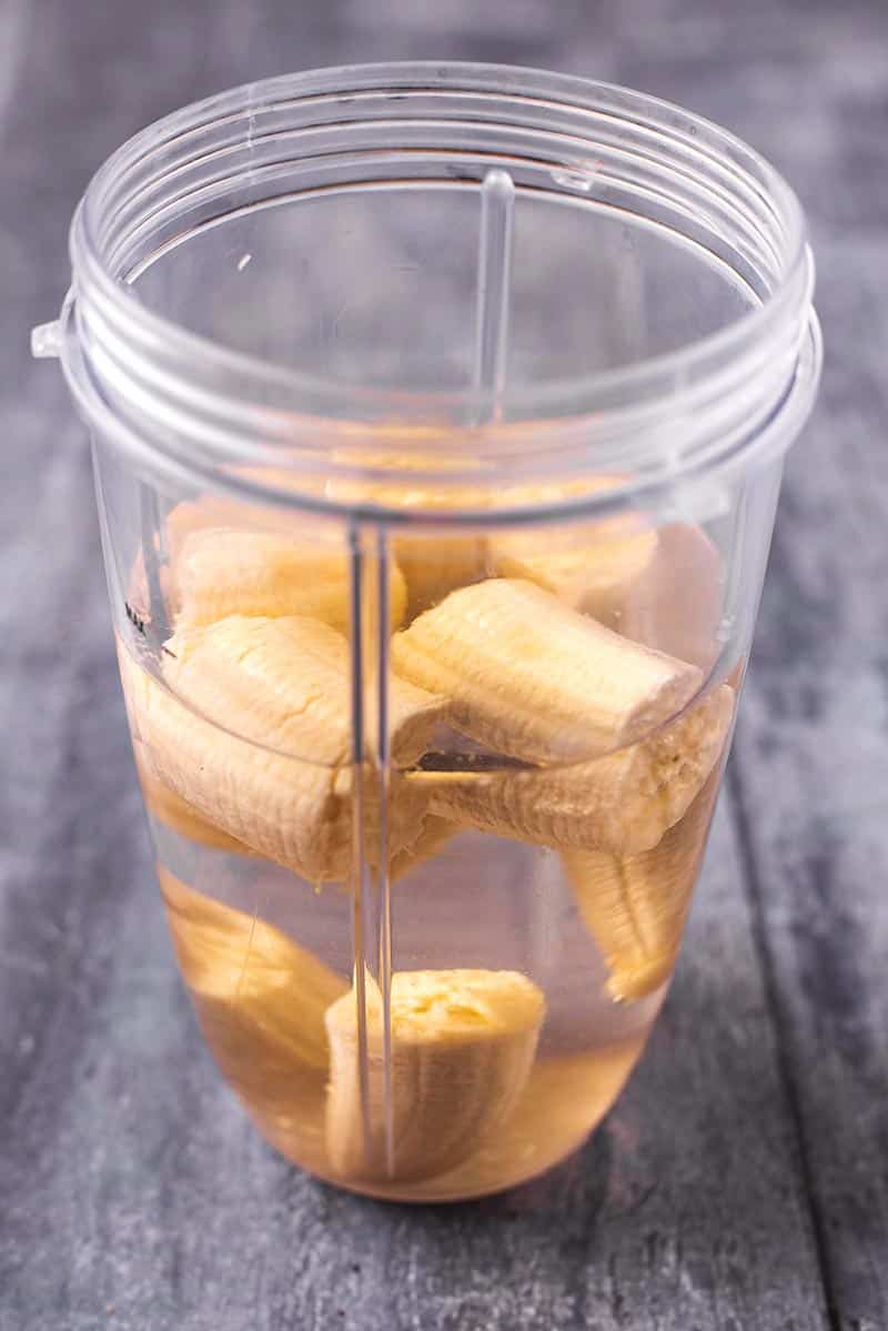 A blender jug filled with water and chunks of banana.