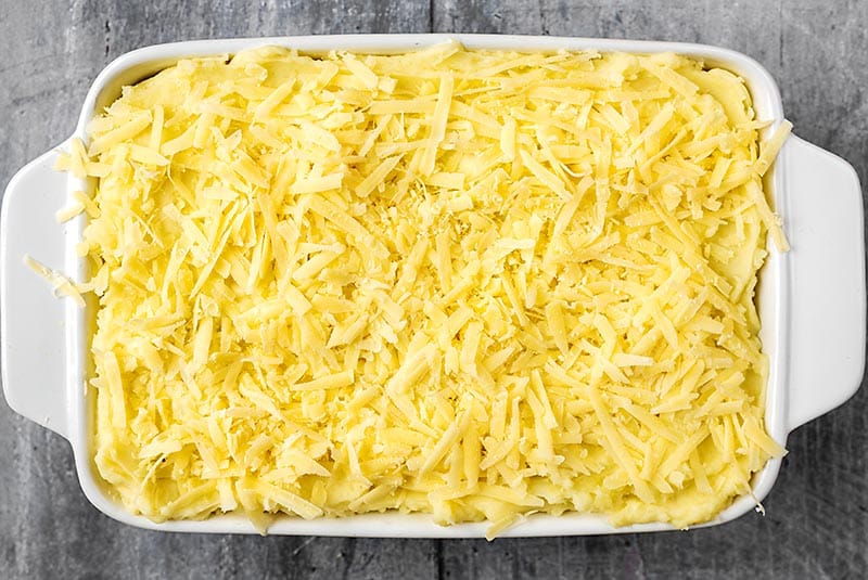 A baking dish with a potato and cheese topped pie.