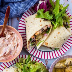 Greek Halloumi Wrap on a platenext to bowls of coleslaw and sliced zucchini