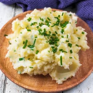 A wooden plate with a large serving of Instant Pot Mashed Potatoes