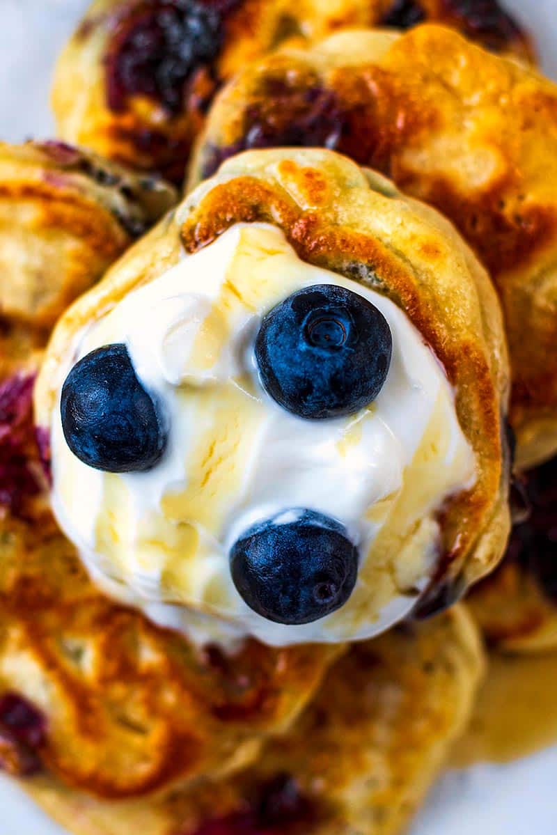 Silver Dollar pancakes topped with yogurt, blueberries and a drizzle of maple syrup.