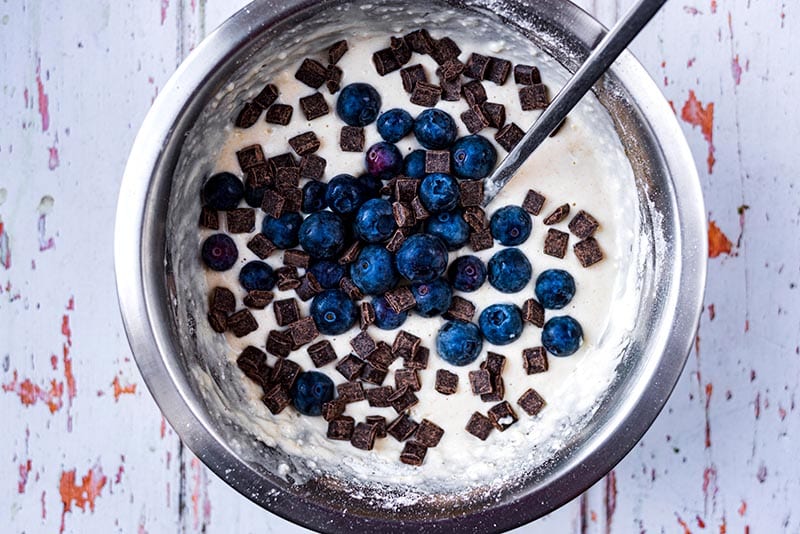 A bowl of pancake batter with blueberries and chocolate chips.