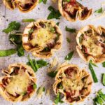 Mini Tortilla Cup Pizzas surrounded by chopped herbs